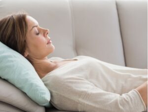 Woman laying down on her sofa receiving distance reiki from Lisa Lazo Foresman of Inner Star Wisdom