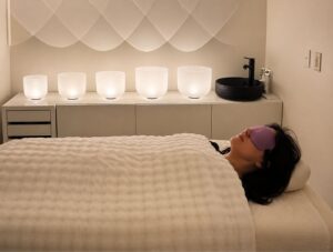 A woman receiving crystal bowl sound healing in a serene room at Inner Star Wisdom in Dallas, TX